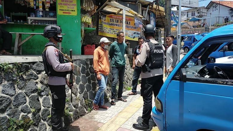 Anggota Sat Brimob Polda Jabar saat memberikan edukasi prokes kepada warga Cipanas.