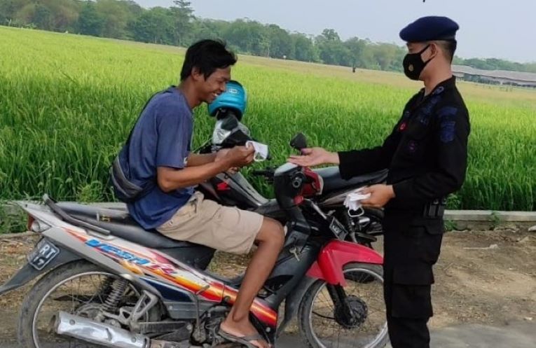 Anggota Sat Brimob Polda Jabar saat memberikan masker kepada warga yang tidak memakai masker.