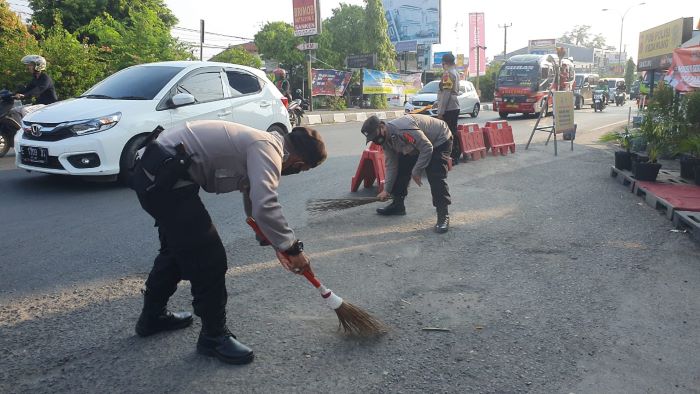 Bahayakan Pengendara, Polisi Bersihkan Bekas Tumpahan Pasir di Sekitar Pos Pam Kedawung